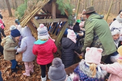 Grupa dzieci ubrana w kolorowe stroje stoją przy pasniku.