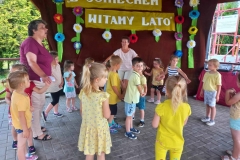 Dzieci w kolorowych strojach stoją jedno obok drugiego na kostce brukowej.