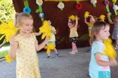 Trzy dziewczynki stoją trzymając w rękach żółte kwiaty