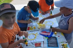 Czterech chłopców wykleja kolorowym papierem słoneczka