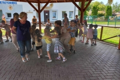 Dzieci stoją jedne za drugim trzymając się za ramiona.