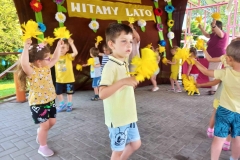 Dzieci stoją trzymając w rękach żółte kwiaty