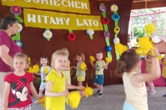 Dzieci stoją w kole, trzymając w rękach żółte kwiaty