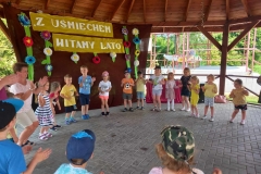 Dzieci stoją w kole. Ubrane są w kolorowe stroje.