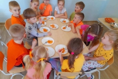 Dzieci siedzą przy stoliku, degustują surówkę z marchewki i jabłka, którą sami wykonali.