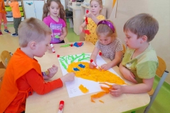 Trzy dziewczynki I dwóch chłopców wykleja marchewkę z bibuły.