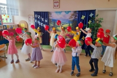 Dzieci stją w dwóch rzędach trzymając czerwone balony.