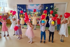 Dzieci stoją w rozsypce trzymając czerwone balony.