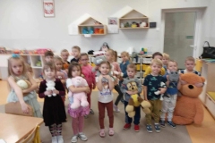 Dzieci stoją w dwuszeregu,  każde przytula  do siebie kolorowego misia.