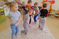 Grupa dzieci biega boso po folii bąbelkowej.