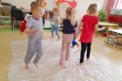 Grupa dzieci biega boso po folii bąbelkowej.