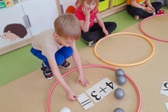 Chłopiec układa działanie matematyczne w obręczy. Obok siedzi dziewczynka.