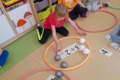 Chłopiec układa działanie matematyczne w obręczy. Obok siedzi dziewczynka.