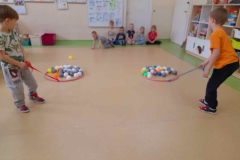 Dwóch chłopców ciągnie kolorowe piłeczki w dwóch obręczach.