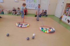 Dziewczynka I chłopczyk ciągną kolorowe piłeczki w obręczach.