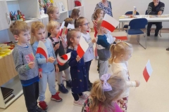 Grupa dzieci trzyma w reku flagi biało czerwone, śpiewają pieśń Przybyli ułani.