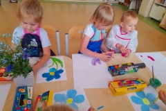 Dwie dziewczynki I chłopczyk malują farbami Niezapominajki.