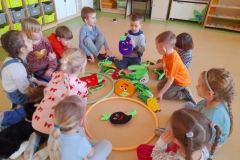 Dzieci siedzą w kole, segregują owoce I warzywa do dwóch obręczy.