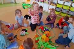 Dzieci siedzą w kole, segregują kolorowe owoce I warzywa do dwóch obręczy.