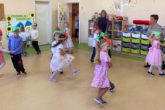 Dzieci tańczą w kole  na głowach mają opaski z jabłuszkiem lub z gruszką, pośród dzieci dwie panie.