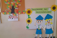 Na zdjęciu widać dwie kolorowe tablice. Na jednej drzewo z jesiennymi listkami na których widać imiona dzieci, na drugiej postać chłopca i dziewczynki. U góry napis, z lewej strony dwa słoneczniki, z prawej jeden.