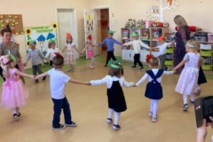 Dzieci tańczą w kole  na głowach mają opaski z jabłuszkiem lub z gruszką, pośród dzieci dwie panie.