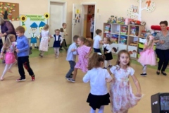 Dzieci tańczą w kole  na głowach mają opaski z jabłuszkiem lub z gruszką, pośród dzieci dwie panie.