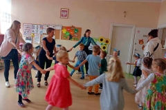 Wiesława Patoń Grupa dzieci stoi w dwóch rzędach, za nimi rodzice, Dyrekcja ZSP, zastępca wójta pani Sabina Nowak. Z prawej strony wychowawczyni. Przed dziećmi kolorowe pompony.