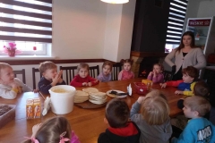 Dzieci siedzą przy stoliku. Na stole stoją  kartoniki z napojem.