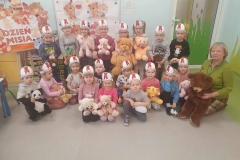 Dzieci wraz z panią siedzą na podłodze.  Każdy  trzyma w rękach pluszowego misia.