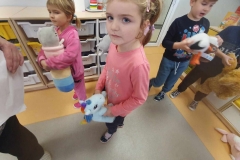 Dwie dziewczynki ubrane w różowe stroje oraz chłopiec ubrany na granatowo. Każde z nich trzyma w rękach pluszowego misia.