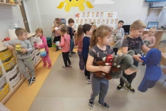 Dzieci wraz z panią poruszają się po kole. W tle widać szafki.