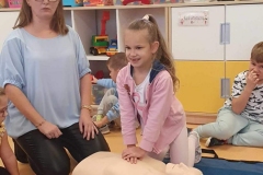 Uśmiechnięta dziewczynka z kucykiem uciskanie klatkę piersiową manekina.Uśmiechnięta dziewczynka z kucykiem uciskanie klatkę piersiową manekina.