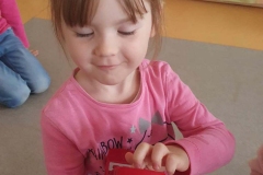 Mała dziewczynka w różowej bluzce trzyma czerwony telefon.