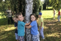 Chłopiec i dziewczynka obejmują biały pień drzewa.