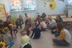 Dzieci wraz z rodzicami zbierają papierowe kwiatki z podłogi.