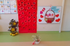 Dekoracja na Dzień Rodziny. Na czerwonej bibułę czerwono czarne kwiatki, na drugiej tablicy kosz z kwiatami i napis.