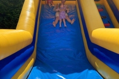  Czwórka dzieci zjeżdża z kolorowego dmuchańca.