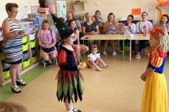 Śnieżka rozmawia z czarownicą. W tle rodzice.