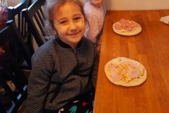 Dwie dziewczynki siedzą przy stoliku, jedzą pizzę. Wiesława