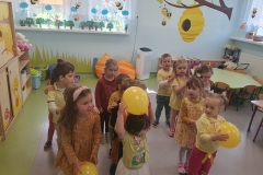 Dzieci ustawione w trzech rzędach. Pierwsze dziecko z każdego rzędu trzyma w rękach żółty balonik.