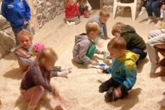 Dzieci bawią się w soli, w tyle widać dziewczynkę, która siedzi na stołku.