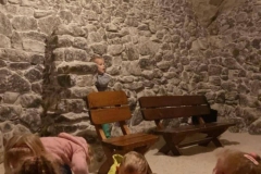 Kilkoro dzieci bawi się solą w grocie solnej. W tle widać ściany z kamienia.