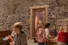 Piecioro dzieci bawi się w soli, w tle widać dwie ławeczki. Zza jednej wychyla się chłopiec.