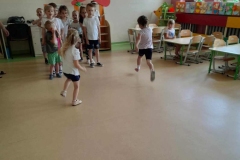 Dwie dziewczynki biegną, w tle dwa rzędy dzieci.