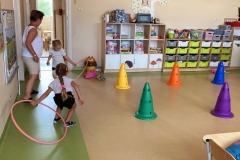 Dwie dziewczynki biegną, w tle dwa rzędy dzieci.