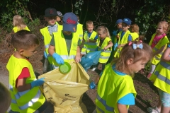 Dzieci wrzucają do żółtego worka znaleziony plastikowy pojemnik.