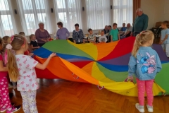 Dzieci bawią się z seniorami chustą animacyjną.