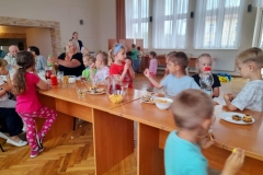 Dzieci wspólnie z seniorami częstują się słodyczami.
