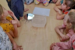 Dzieci zgromadzone wokół stolika na którym leżą przedmioty do eksperymentu.